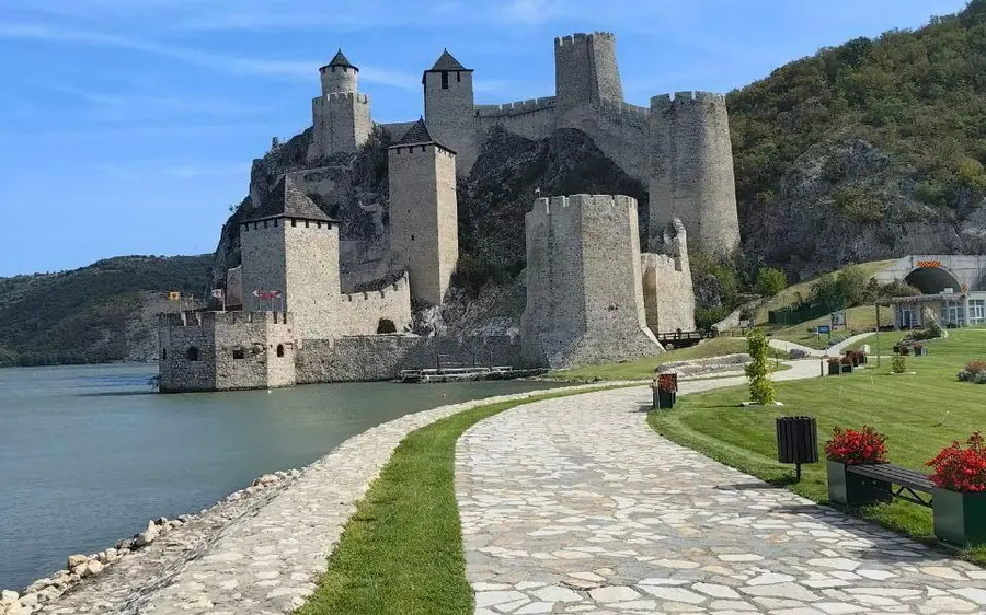 La forteresse depuis la pelouse et le chemin pavé le long de la rive, les tours s&rsquo;élevant derrière