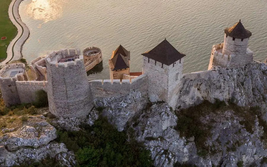 Vue aérienne de tours de pierre aux toits de bardeaux sur une crête rocheuse au-dessus d&rsquo;une eau pâle