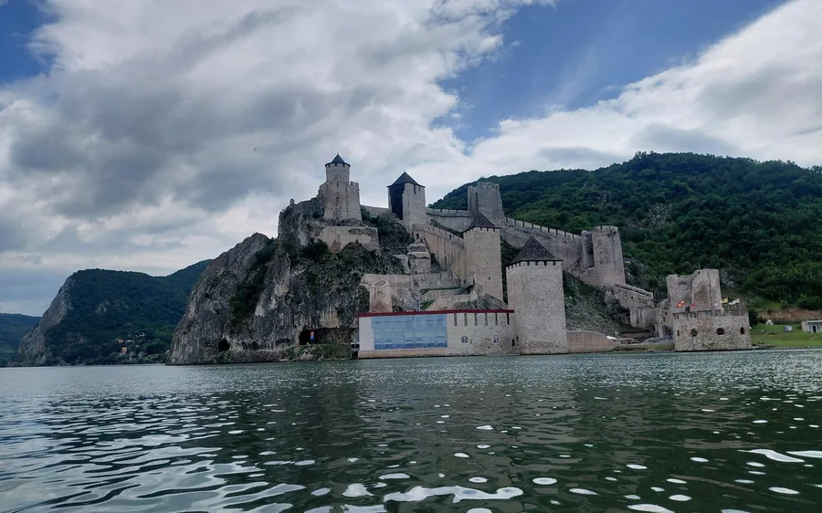 La forteresse sur son promontoire boisé vue de bas, depuis l&rsquo;eau grise et agitée du fleuve
