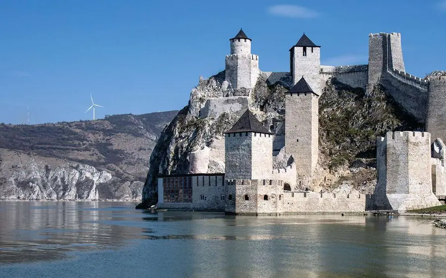 Tours blanches sur un éperon rocheux au-dessus du fleuve, éoliennes sur la crête au loin