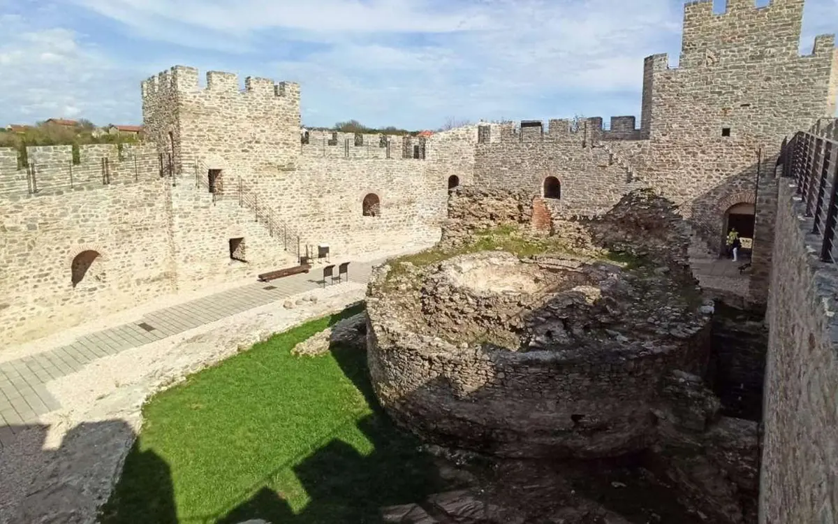 De l&rsquo;herbe, la base d&rsquo;une tour ronde en pierre et les remparts à l&rsquo;intérieur de la forteresse de Golubac